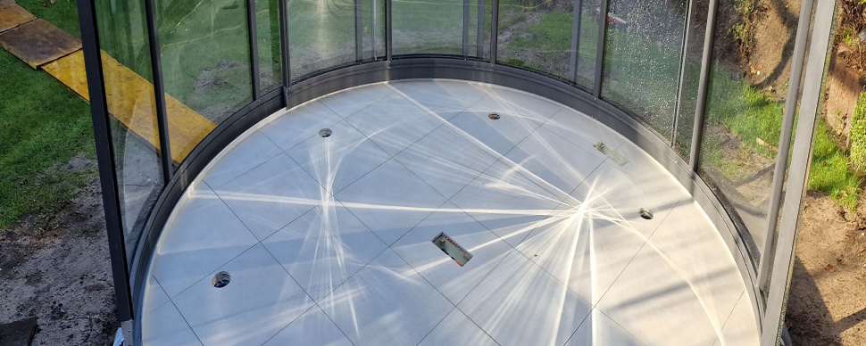 Runde Außenterrasse mit grauen Fliesen im Garten in sonniger Lage.